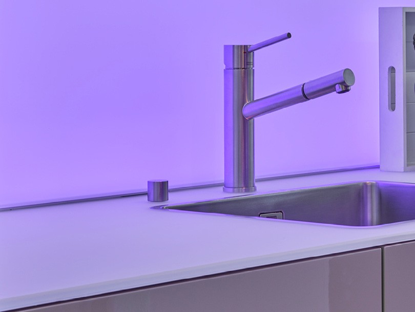 küchenabdeckung aus glas mit lila hintergrund licht und armatur